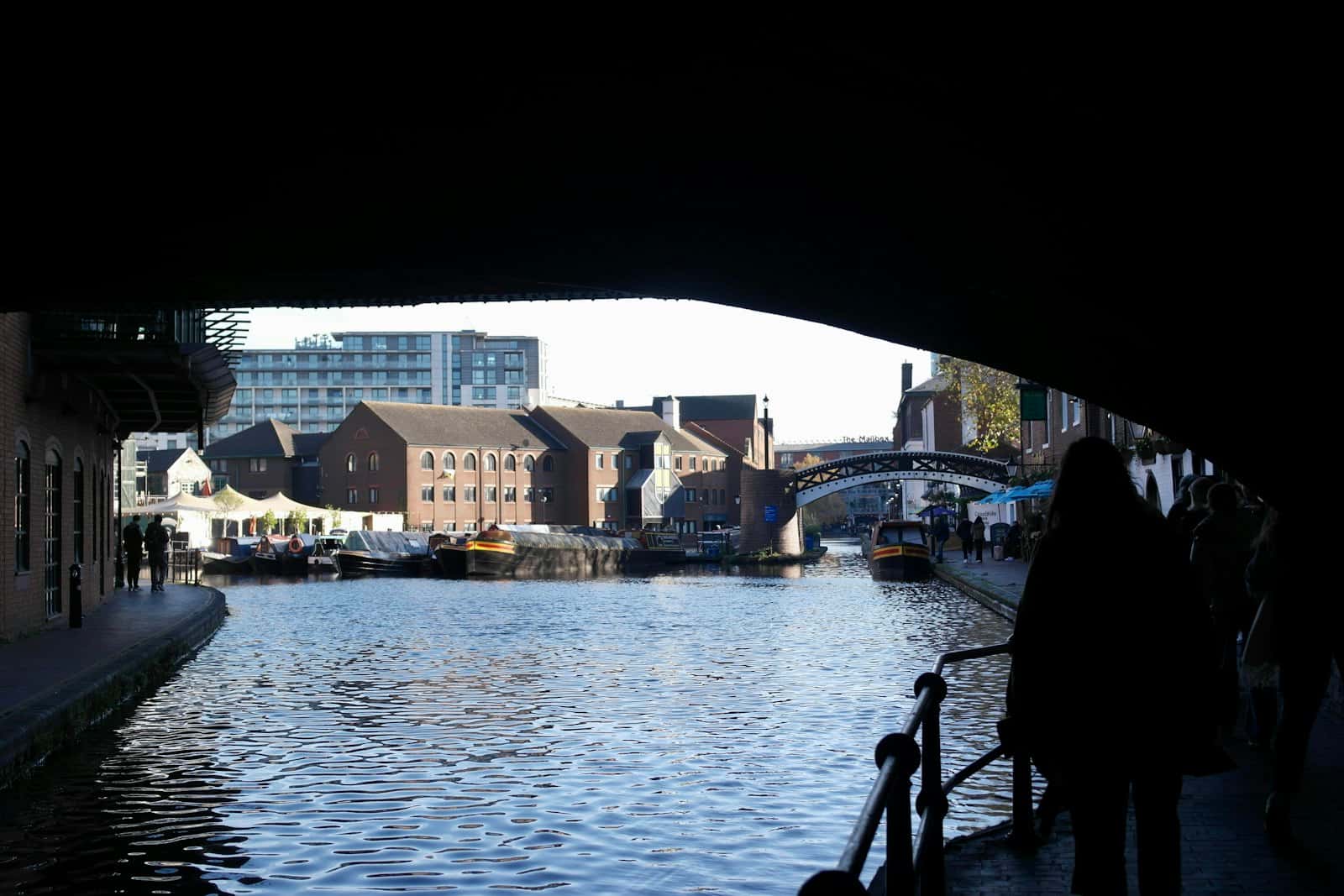 A person on a canal bridge in Birmingham with buildings either side